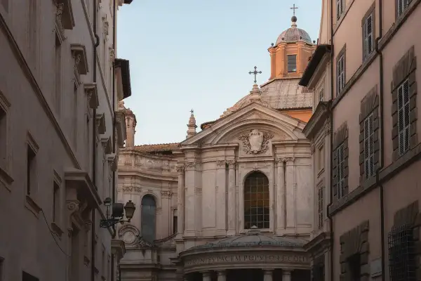 La facciata barocca della chiesa di Santa Maria della Pace si staglia tra palazzi romani, con la sua cupola imponente e le decorazioni scultoree.