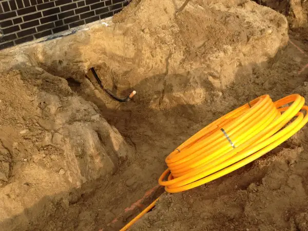 Baustelle: gelbe Rohre liegen bereit für die Gasleitung verlegen im Erdreich. Ein Graben ist ausgehoben.