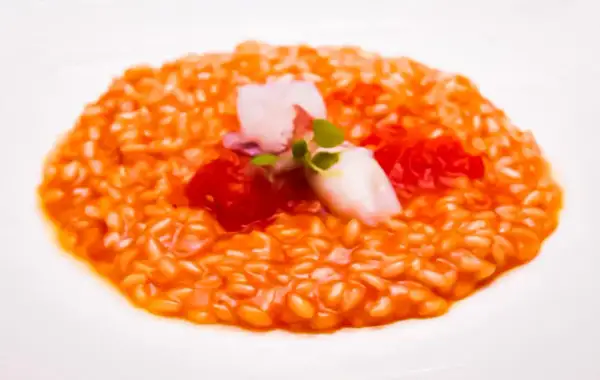 Risotto al porto cremoso con gamberi, pomodorini e un tocco di verde.
