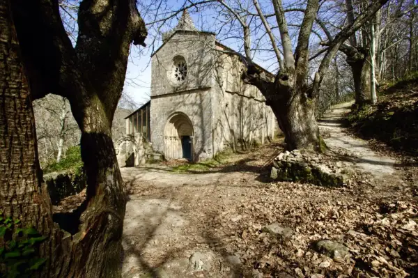Antiguo monasterio Santa Cristina, rodeado de árboles desnudos y hojas secas. Un camino serpentea hacia la entrada principal.