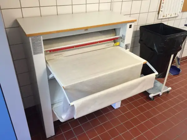 Stor mangel med ett vitt lakan som rullas ut. En stor svart soptunna står bredvid.