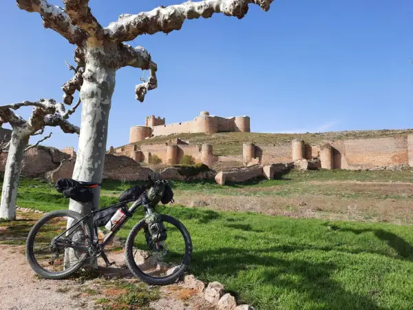 Bicicleta de montaña lista para rutas en bici por Soria, con un castillo medieval al fondo.
