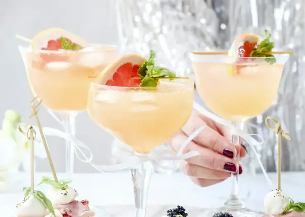Tre eleganta glas med rosa drinkar, garnerade med grapefrukt och mynta. Perfekt drink till nyår!