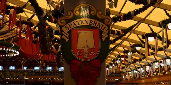 Spatenbräu-Schild mit Schaufel-Symbol, das auf die Herkunft des Bieres hinweist. Festlich geschmückte Halle.