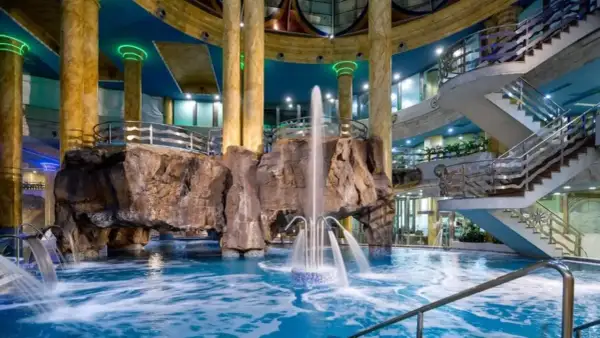 Interior de un balneario en la Comunidad Valenciana con piscina, cascadas, rocas artificiales y escaleras.