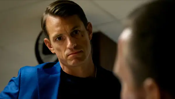 Joel Kinnaman i blå kavaj, intensiv blick mot någon i närbild. Ser ut som en scen från en ny serie.
