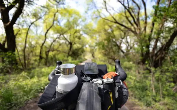 Widok z kierownicy roweru podczas bikepacking gravel. Biała butelka, nawigacja i torba podsiodłowa gotowe na przygodę.