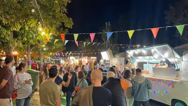 Noche animada en un festival de ebro food trucks, con luces, banderas y gente disfrutando.