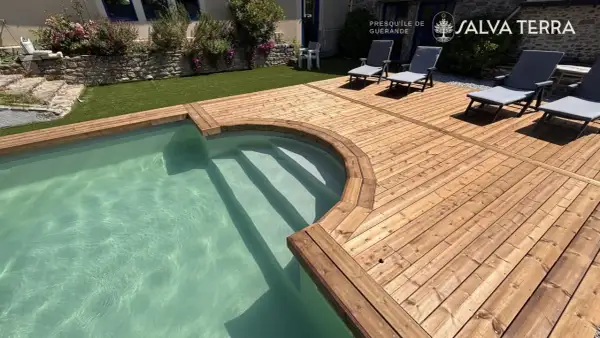 Terrasse en bois classe 3 ou 4, bordant une piscine aux eaux claires. Des chaises longues invitent à la détente sur ce bois chaleureux.