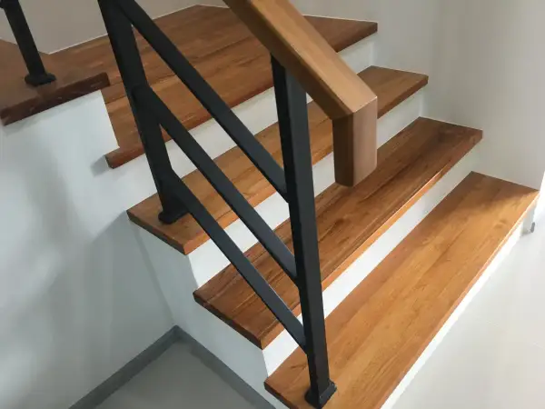 Moderne Treppen aus Holz mit schwarzem Geländer in einem Einfamilienhaus.
