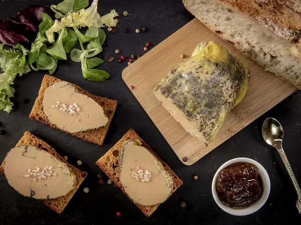 Tranches de foie gras sur toasts, accompagnées de pain frais, d'une compotée de fruits et d'une touche de cognac ou d'armagnac.