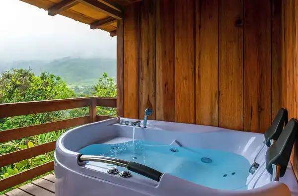 A newly completed hot tub installation on a wooden deck, overlooking a misty mountain landscape.