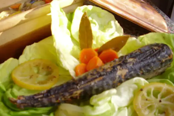 Un maquereau au vin blanc, servi sur un lit de laitue avec des carottes et des rondelles de citron.