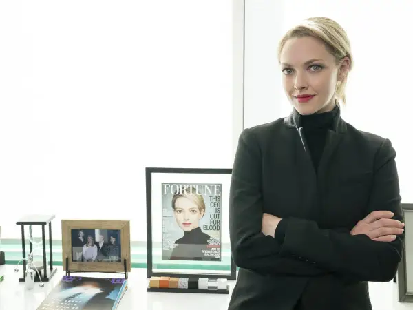 Amanda Seyfried som Elizabeth Holmes i "The Dropout", med armarna i kors och en tidning med hennes ansikte på.