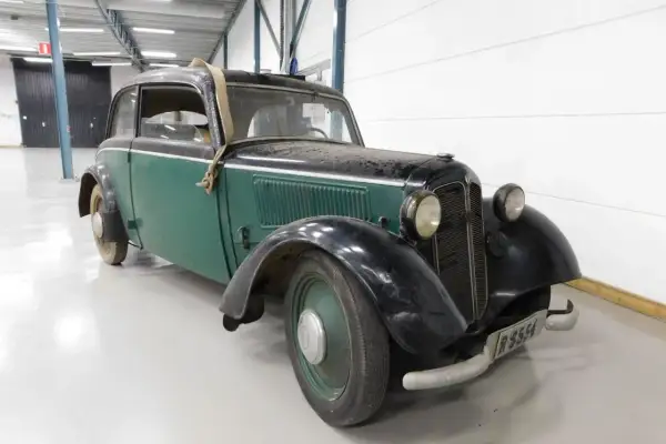 En grön och svart DKW med en spånkorgsdetalj på taket, står i ett garage.