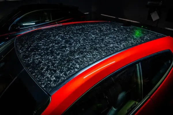 Dach samochodu pokryty unikalnym wzorem forged carbon. Intensywny czerwony lakier kontrastuje z czarno-białym, nieregularnym deseniem.