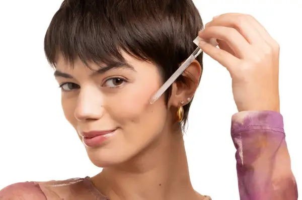 Una donna applica un siero viso con contagocce. Scopri a cosa serve la vitamina C per il viso per una pelle luminosa.