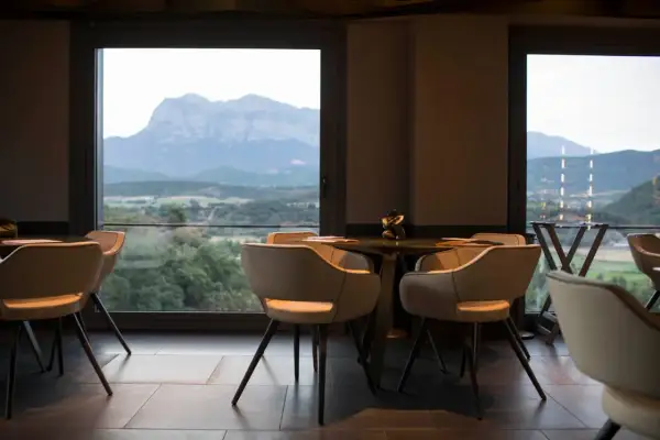 Mesas y sillas en un restaurante con vistas a montañas y valles, como si fueran soles Repsol en Aragón.