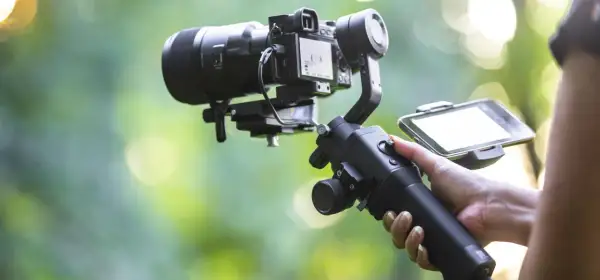 Ręka trzymająca stabilizator do kamery, czyli co to gimbal. Umożliwia płynne nagrywanie filmów.