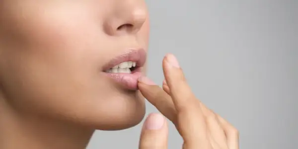 Une femme applique un baume sur ses lèvres. Si vous avez des lèvres gercées, que faire ? Hydratez-les !