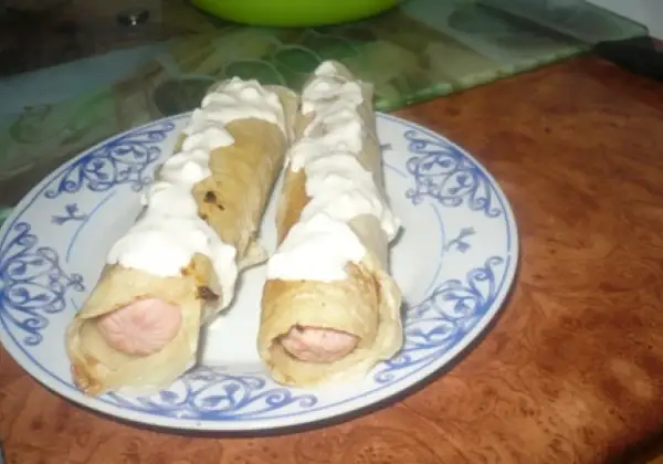 Dwa parówki w cieście naleśnikowym, polane sosem. Pyszna przekąska na szybko.