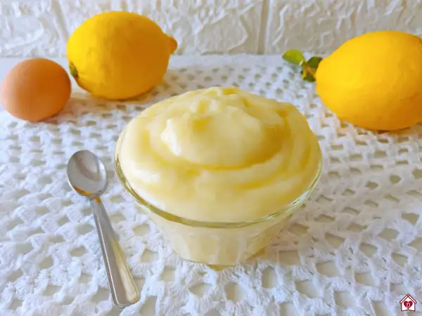 Crema pasticcera al limone, soffice e profumata, pronta per essere gustata. Accanto, un uovo e limoni freschi.