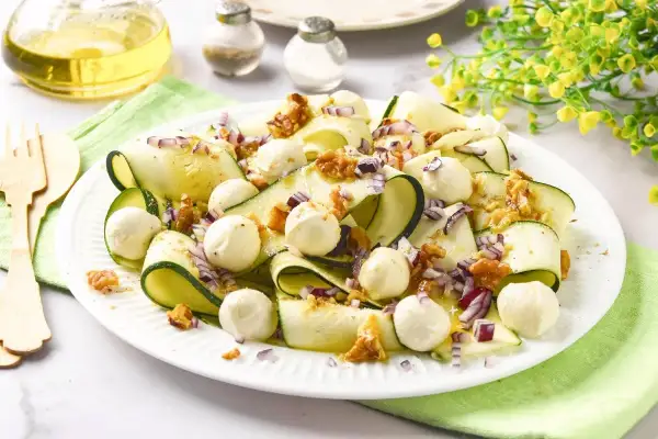 Deliciosa ensalada de calabacín en cintas, con bolitas de mozzarella, nueces y cebolla morada. Un plato fresco y ligero.