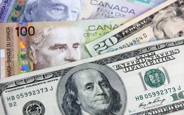 Kanadyjski dolar i amerykańskie banknoty, w tym 100 dolarów kanadyjskich i 100 dolarów amerykańskich, tworzą finansową mozaikę.