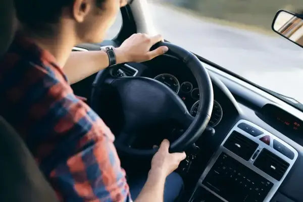 Mężczyzna w kratę prowadzi auto. Zastanawiasz się, co to jest amortyzacja samochodu? To proces zużywania się pojazdu.