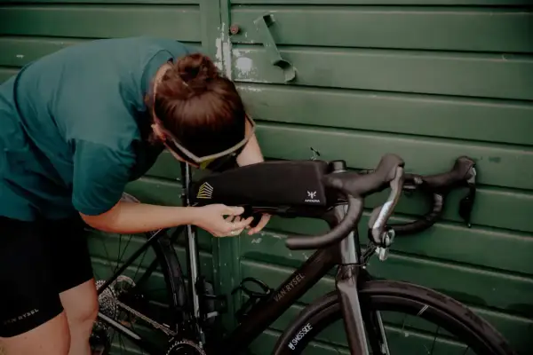 Osoba montuje torbę podsiodłową do roweru. Przygotowania do składania roweru przed wyprawą.