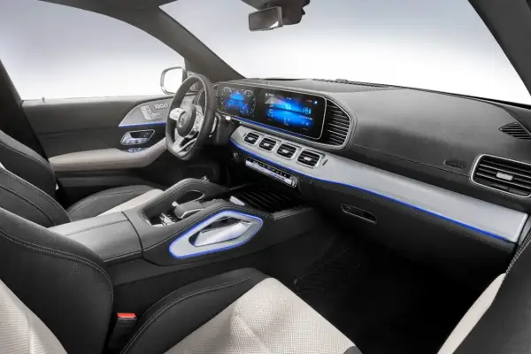 Interior de un Mercedes moderno, con pantallas digitales, asientos de cuero y detalles de iluminación ambiental azul.