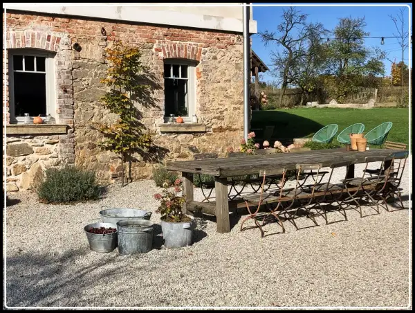 Rusty metal chairs await guests at a rustic table outside a stone building. Ideal agroturystyka Dolny Śląsk.