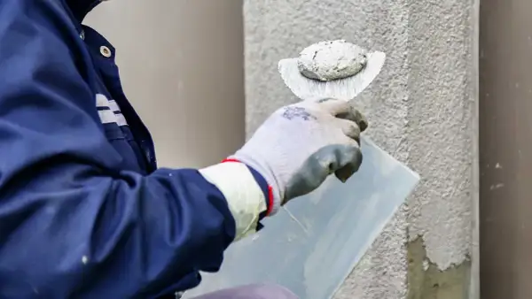 Pracownik nakłada tynk silikonowy na ścianę. Sprawdź atrakcyjną cenę za m2 robocizny.