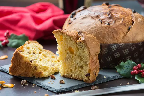 Un delicioso panettone, un dulce navideño italiano, cortado en rebanadas, con pasas y frutas confitadas.