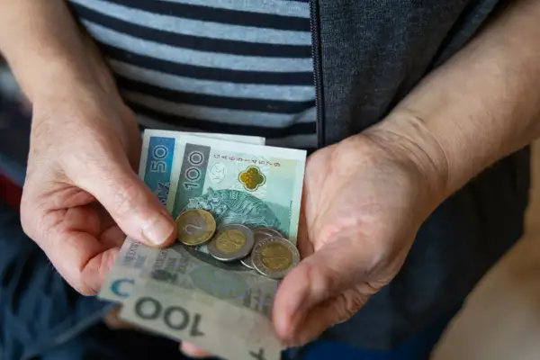 Dłonie trzymają banknoty 50 i 100 zł oraz monety. Czy to odzwierciedla średnią emeryturę w Polsce?