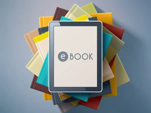 Une tablette affiche "e BOOK" au milieu d'une pile de livres colorés. C'est quoi un ebook ? Une nouvelle façon de lire !