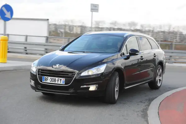 Czarny Peugeot 508 GT na drodze, przygotowany do wymiany żarówki z przodu.