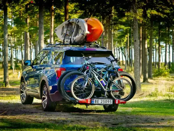 Gotowi na przygodę! Błękitny SUV z rowerami na bagażniku i kajakami na dachu, idealny na pętlę bieszczadzką.
