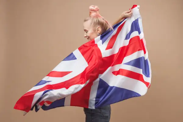 Joven con cabello rosa ondea la bandera del Reino Unido, un símbolo de las tradiciones de Reino Unido.