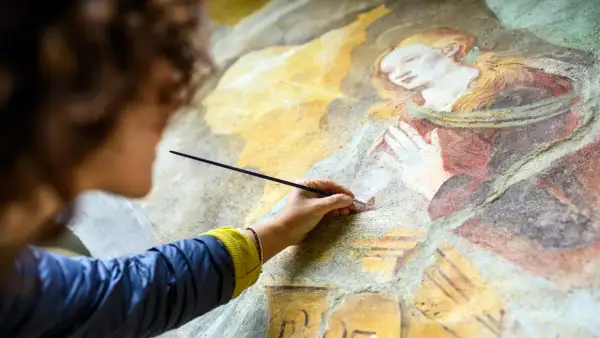Restauration d'une vieille peinture qui sent mauvais, une main délicate redonne vie à une fresque ancienne.