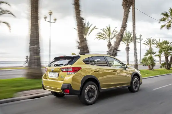 Złoty Subaru XV 2.0 benzyna jedzie wzdłuż nadmorskiej promenady, mijając palmy i biegacza.