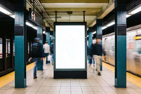 Gente se mueve rápido en el metro de Nueva York, pasando un anuncio en blanco.