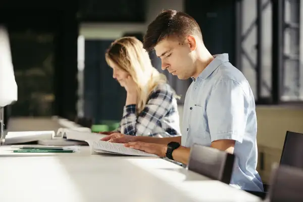 Estudiantes concentrados estudiando para entender como funcionan las oposiciones de maestro.