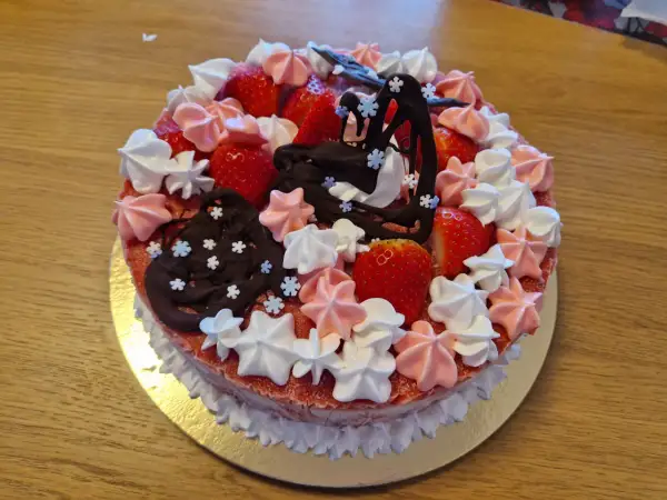 En jordgubbstårta med klassiska tårtor namn, dekorerad med maränger, choklad och färska jordgubbar.