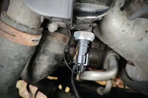 Czujnik ciśnienia oleju 1.9 TDI znajduje się w pobliżu metalowych rur i przewodów silnika.
