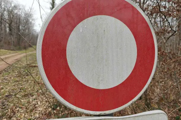 Panneau rond rouge et blanc, interdisant le passage sur un chemin forestier.
