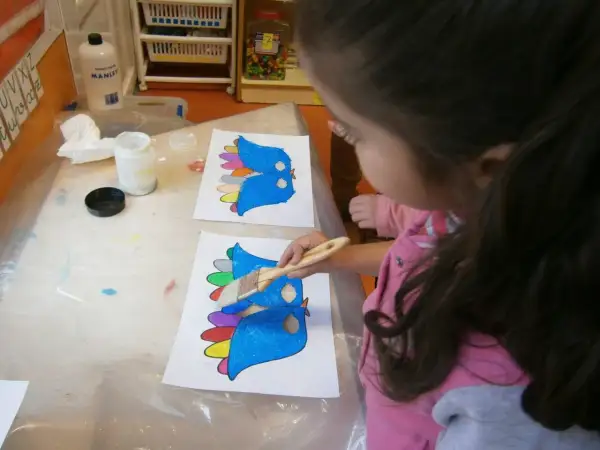 Niña pinta pájaros de colores, preparándose para un día de la paz para niños.