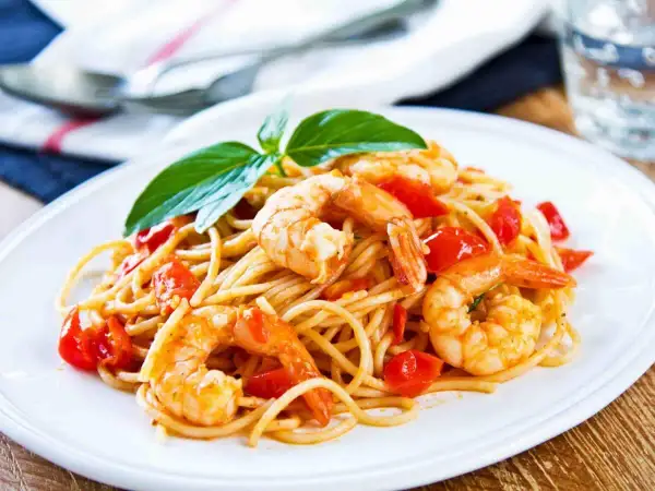 Spaghetti con gamberetti succulenti e pomodorini freschi, guarniti con basilico. Un piatto invitante che profuma di mare.