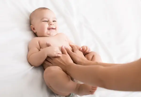 Glad bebis får magmassage på en vit bakgrund.