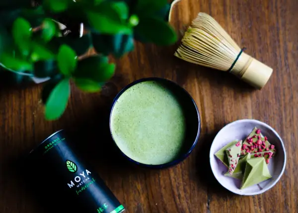 Zielone, spienione matcha w miseczce, obok bambusowa miotełka i czekoladki. To może być najdroższa herbata na świecie, przygotowana z pasją.